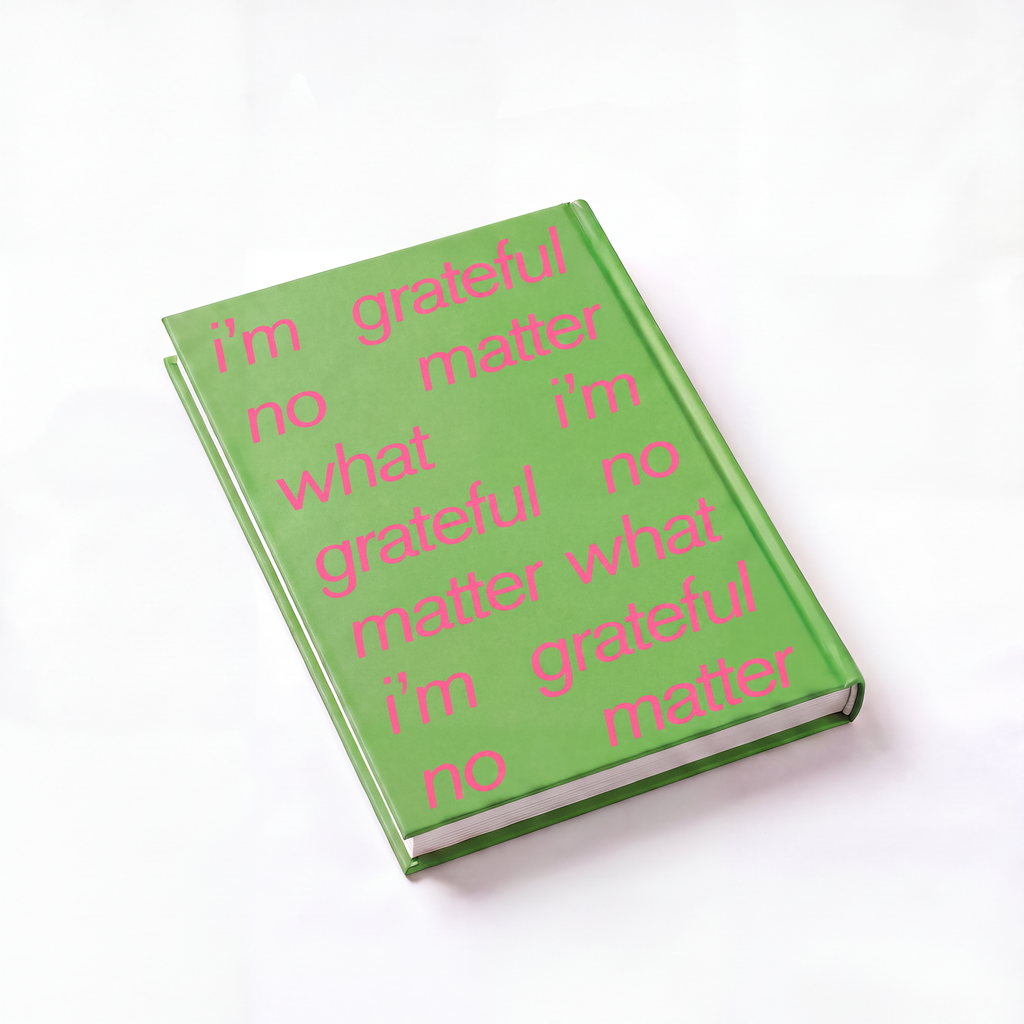 A hardcover book with a bright green cover and pink text that reads 'i'm grateful no matter what i'm grateful no matter what' repeated across the cover, photographed on a clean white background.
