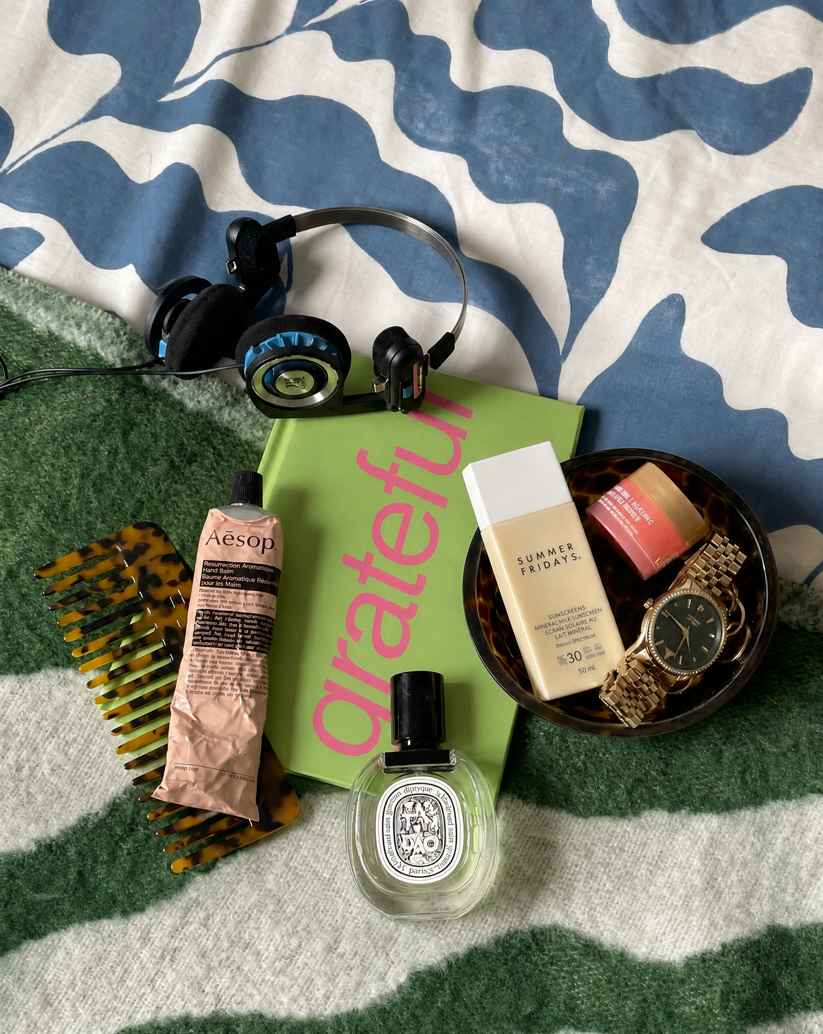 Various items including a bottle, hairbrush, and book on a patterned surface