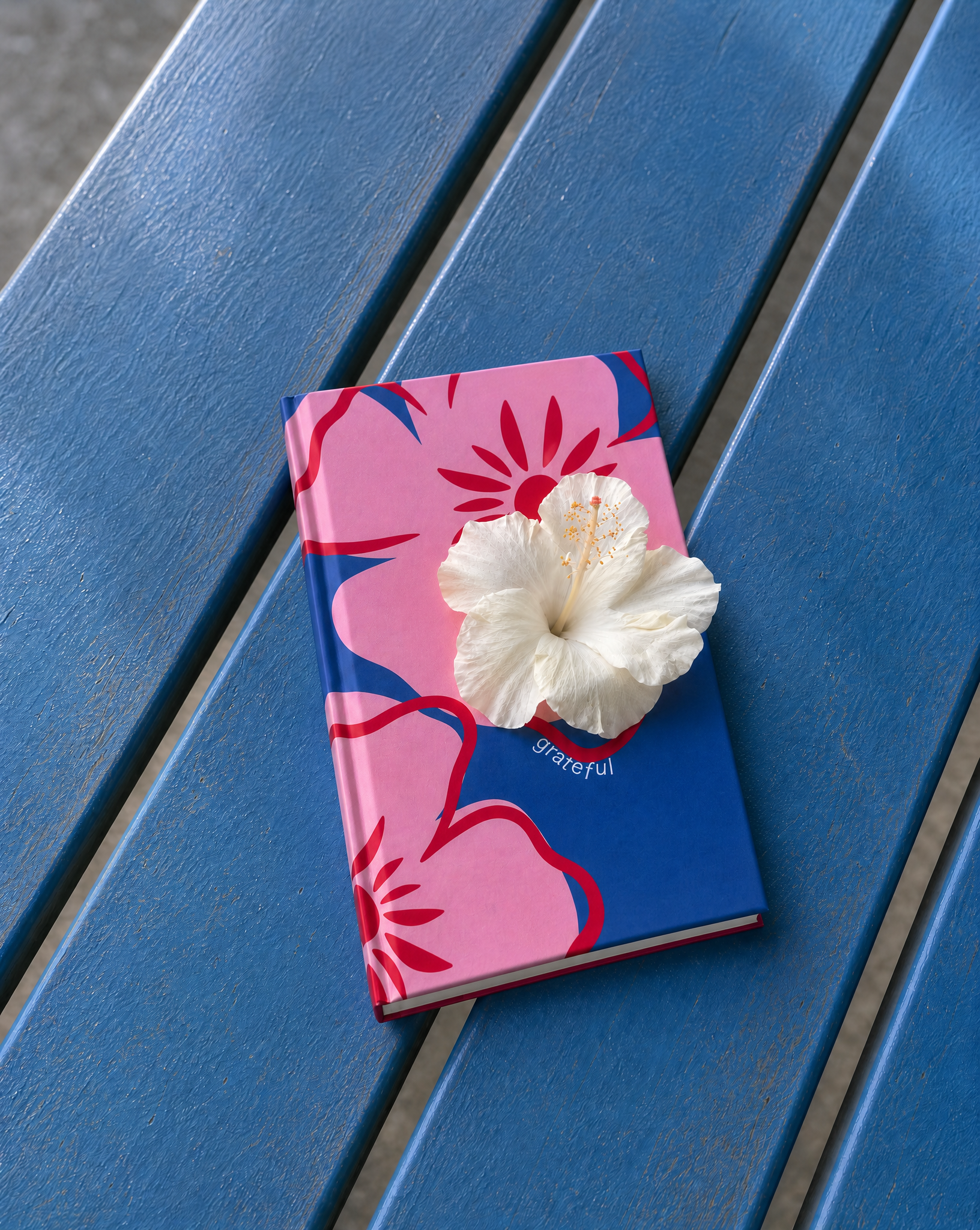 Floral notebook with a white flower on a blue bench