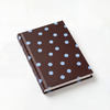 Brown notebook with blue polka dots on a white background